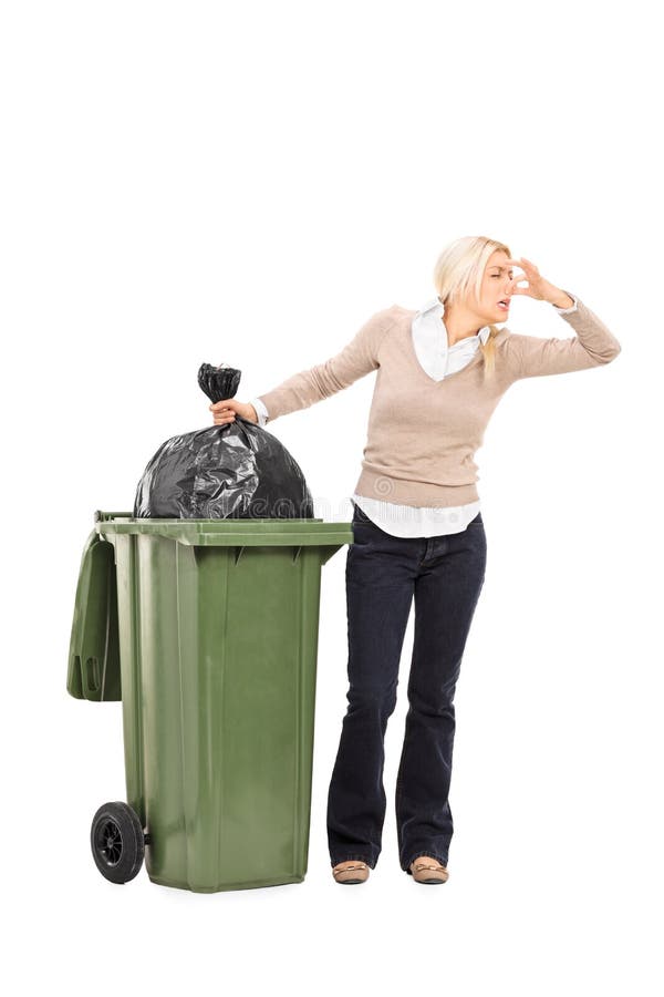 Full length portrait of a disgusted woman standing next to a trash can isolated on white background. Full length portrait of a disgusted woman standing next to a trash can isolated on white background