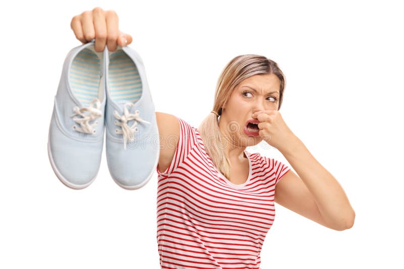 Disgusted woman holding a pair of stinky shoes isolated on white background. Disgusted woman holding a pair of stinky shoes isolated on white background