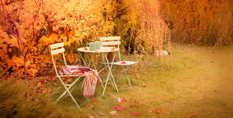 Angolo variopinto del giardino di autunno con tè e la coperta caldi fotografie stock libere da diritti Angolo variopinto del giardino di autunno con tè e la coperta caldi fotografie stock libere da diritti