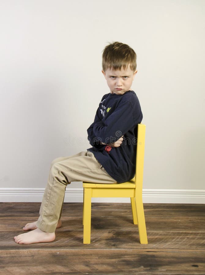 Angry boy on a yellow time out chair