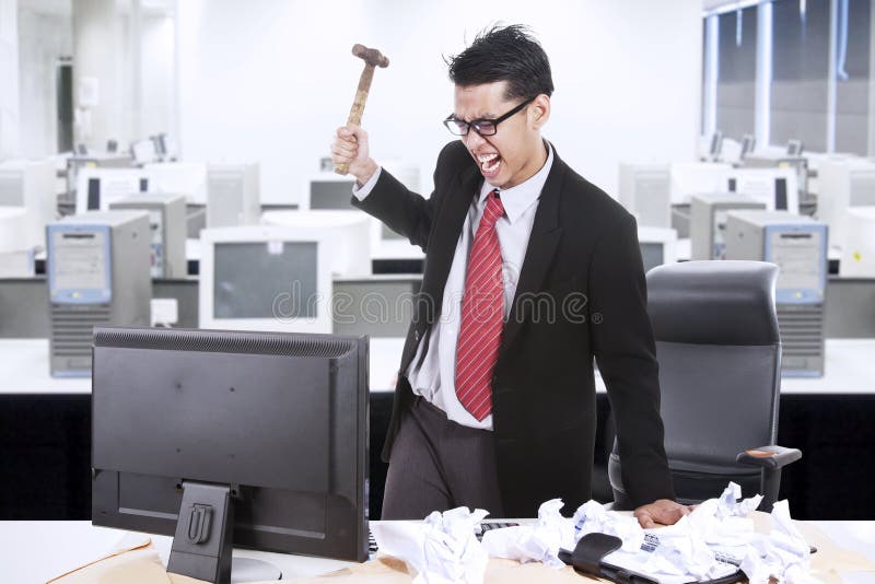 Angry businessman throw hammer at computer