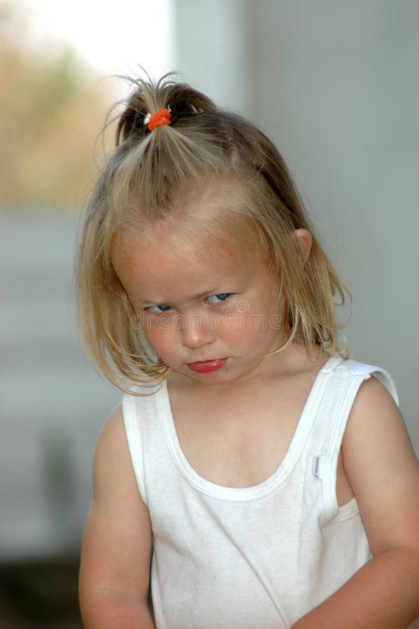 A beautiful little blond blue eyed toddler girl being very angry with her parents showing the disappointed expression in her face. A beautiful little blond blue eyed toddler girl being very angry with her parents showing the disappointed expression in her face.