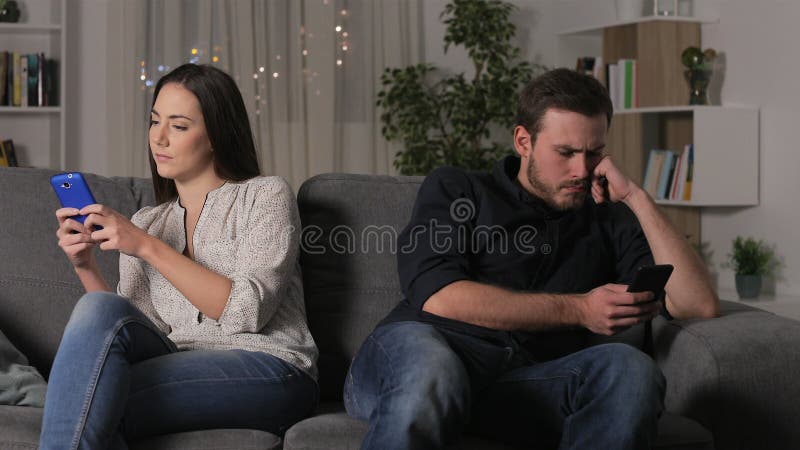 Angry couple using their smartphones after argument