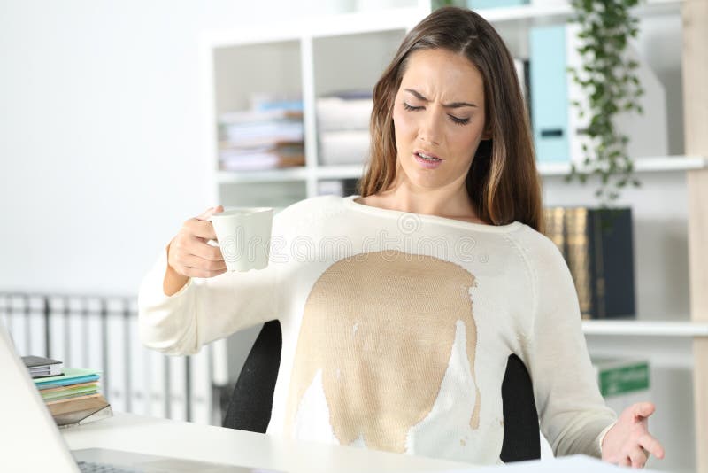 Angry executive with spilled coffee over her shirt at office.