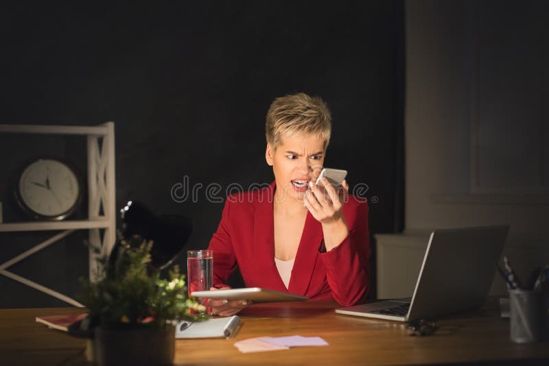 Angry girl at office shouting on mobile, staying late at working