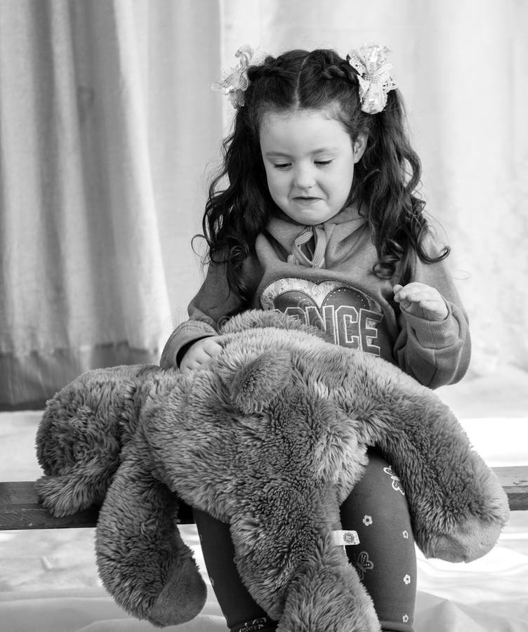 Angry little girl beating her teddy bear - domestic abuse concept. Girl 4-5 year old punishes toy bear