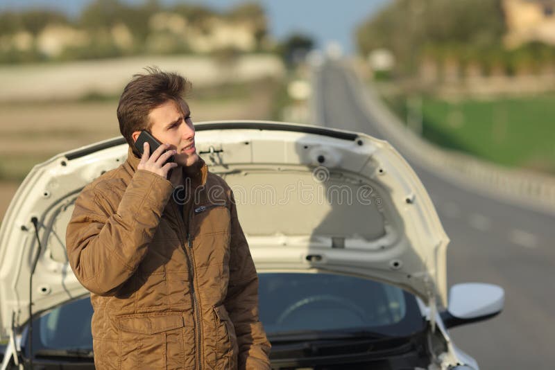 Angry man calling roadside assistance for his breakdown car in a road in winter