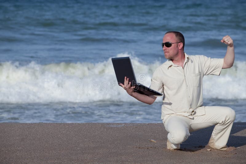 Angry man punching laptop at the beach royalty free stock photography