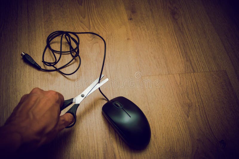 Angry man snijdt de draad van de computermuis met schaar op een donkere achtergrond, het concept vrijheid van draden stock foto Angry man snijdt de draad van de computermuis met schaar op een donkere achtergrond, het concept vrijheid van draden stock foto