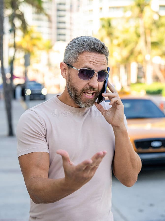 Angry Mann telefoniert in der Stadt. Mann mit Handy in der Stadt rufen. Reife gestresste Person per Telefon. Hispanic-Typ ruft an lizenzfreie stockfotos