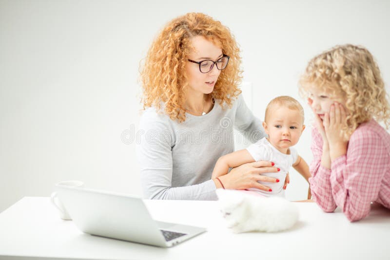 Angry mother is holding interfering little baby as she cannot do her work. women is going to show a cartoon to her children . close up side view shot