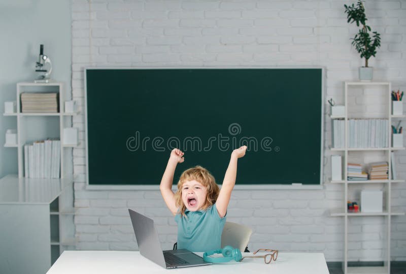 Angry sad screaming kid boy shouting on lesson at school, making homework and using notebook gadget. Bad school boy.