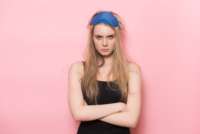 Angry sad sleepy woman just woke up and standing unhappy with arms crossed wearing sleeping mask