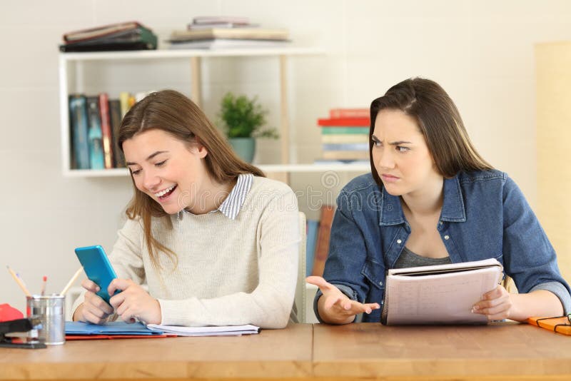 Angry student looking at her lazy mate stock image