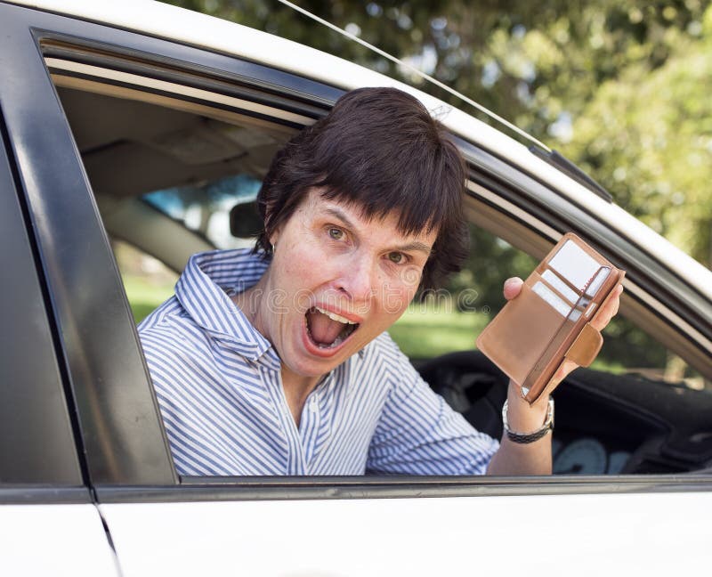 A middle-aged woman sitting in her car looks very upset as she finds her wallet missing credit cards and money. A middle-aged woman sitting in her car looks very upset as she finds her wallet missing credit cards and money.