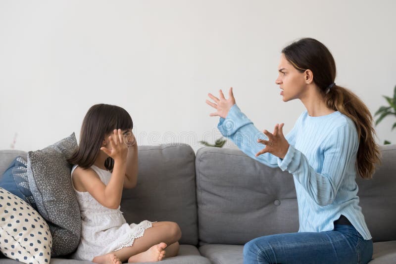 Mad young mom an little daughter sit on couch have fight arguing gesturing, furious angry mother yell dispute with preschooler girl, annoyed parent lecture small child imitating play pretend similar. Mad young mom an little daughter sit on couch have fight arguing gesturing, furious angry mother yell dispute with preschooler girl, annoyed parent lecture small child imitating play pretend similar