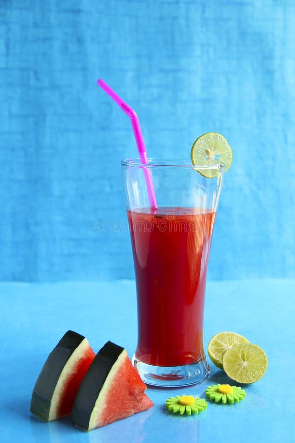 Anguria affettata e succo decorati con il limone, isolato su fondo blu-chiaro immagini stock Anguria affettata e succo decorati con il limone, isolato su fondo blu-chiaro immagini stock
