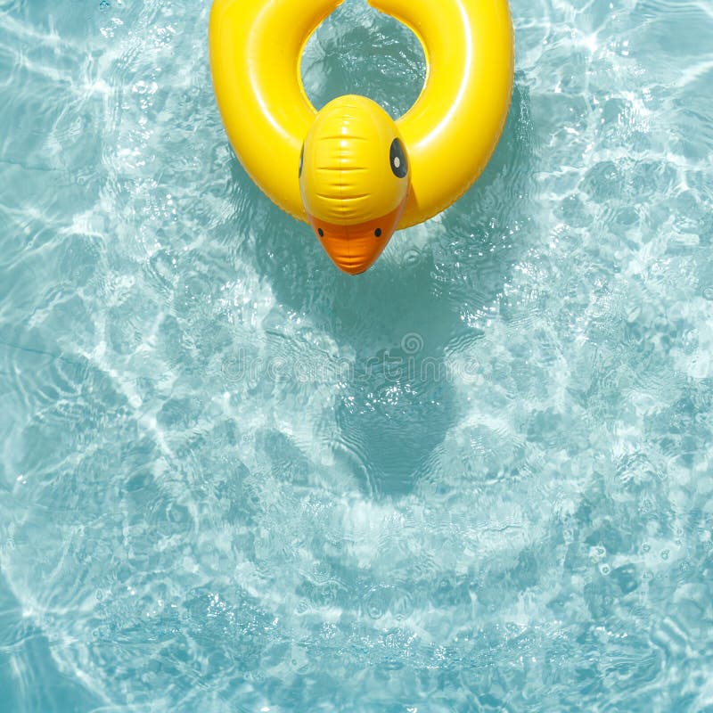 Anillo de caucho flotante inflable en forma de pato amarillo en agua azul imagenes de archivo Anillo de caucho flotante inflable en forma de pato amarillo en agua azul imagenes de archivo