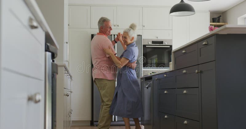 Animación de feliz pareja caucásica mayor bailando en la cocina almacen de video