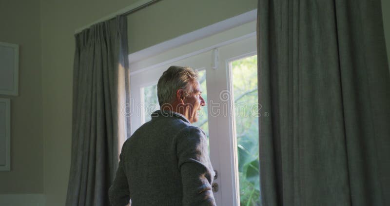 Animación de un feliz hombre de edad caucásica revelando cortinas almacen de video