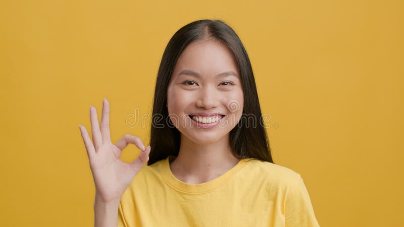 Animada asiática gestando bem sorrindo para o fundo amarelo da câmera