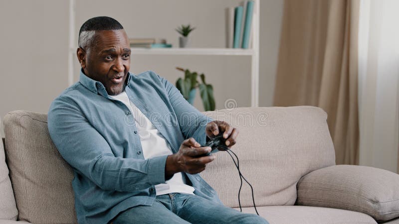 Uma menina sentada no sofá jogando um vídeo na sala de estar em casa. mão  de menina gamer animado segurando o joystick jogando jogo de console usando  um controlador sem fio.