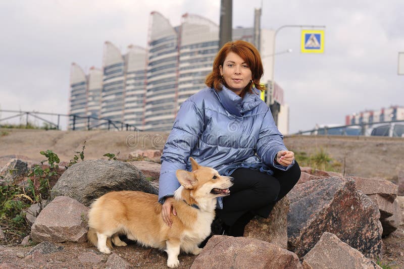 Pet on a walk - Welsh Corgi Pembroke redhead with yellow coloring and girl. Pet on a walk - Welsh Corgi Pembroke redhead with yellow coloring and girl