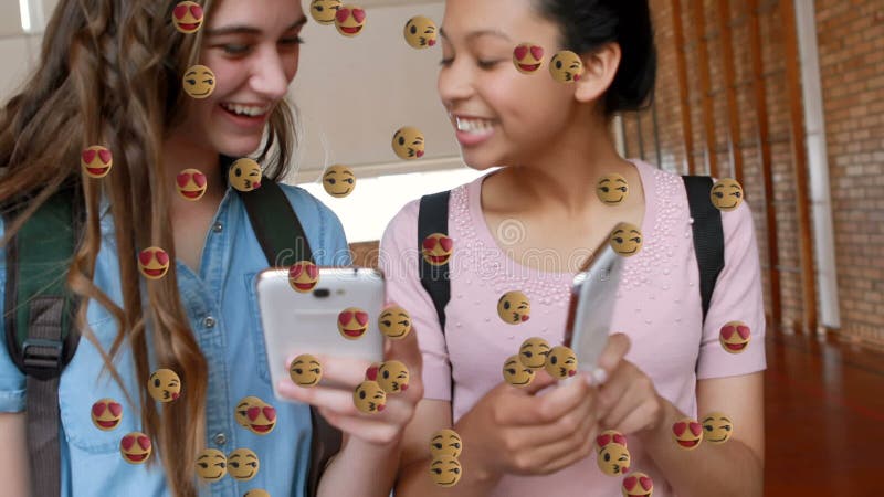 Multiple face emojis floating against two female students using smartphones