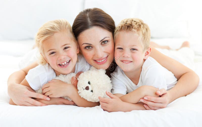 Animated siblings with their mother lying on a bed at home. Animated siblings with their mother lying on a bed at home