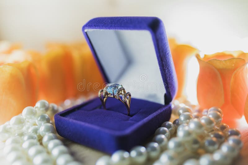 Anneau d'or avec la topaze dans un boîte-cadeau sur des perles image stock Anneau d'or avec la topaze dans un boîte-cadeau sur des perles image stock