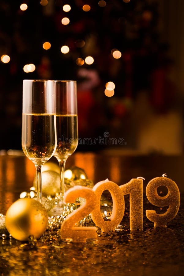 New Years Eve celebration background with pair of flute,candles forming the 2019 number, glitter and defocused background, with christmas tree light forming a nice bokeh, holiday concept, frontal view,,copyspace. New Years Eve celebration background with pair of flute,candles forming the 2019 number, glitter and defocused background, with christmas tree light forming a nice bokeh, holiday concept, frontal view,,copyspace