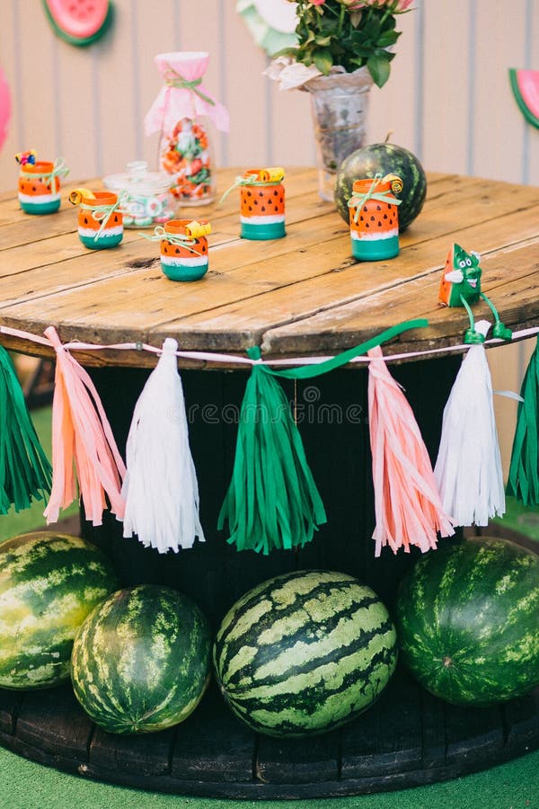 Anniversaire en bois de vacances du ` s d'enfants de table de pique-nique avec des pastèques, décor des rubans blancs et roses et images libres de droits Anniversaire en bois de vacances du ` s d'enfants de table de pique-nique avec des pastèques, décor des rubans blancs et roses et images libres de droits