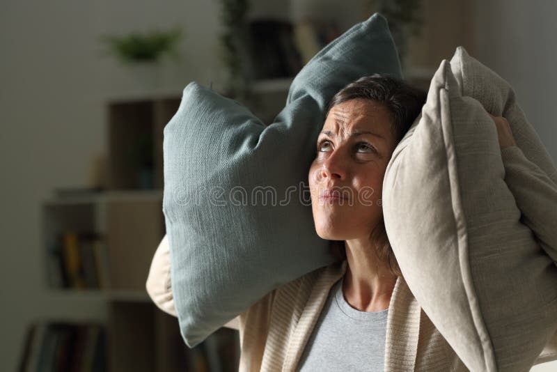 Annoyed adult woman suffering neighbour noise in the livingroom at night at home. Annoyed adult woman suffering neighbour noise in the livingroom at night at home