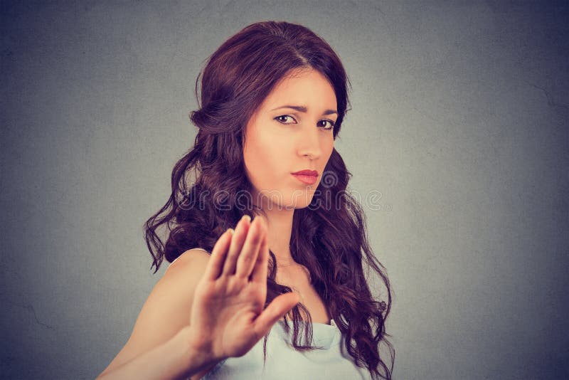 Closeup portrait young annoyed angry woman with bad attitude giving talk to hand gesture with palm outward grey wall background. Negative human emotion face expression feeling body language