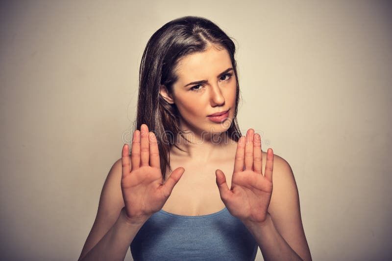 Closeup portrait young annoyed angry woman with bad attitude gesturing with palms outward to stop isolated on grey wall background. Negative human emotion face expression feeling body language. Closeup portrait young annoyed angry woman with bad attitude gesturing with palms outward to stop isolated on grey wall background. Negative human emotion face expression feeling body language