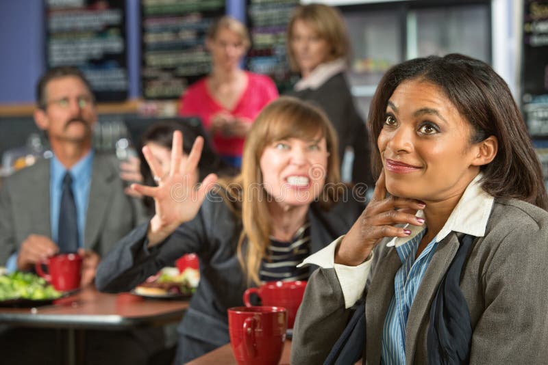 Annoyed coworker behind smiling business women in cafeteria