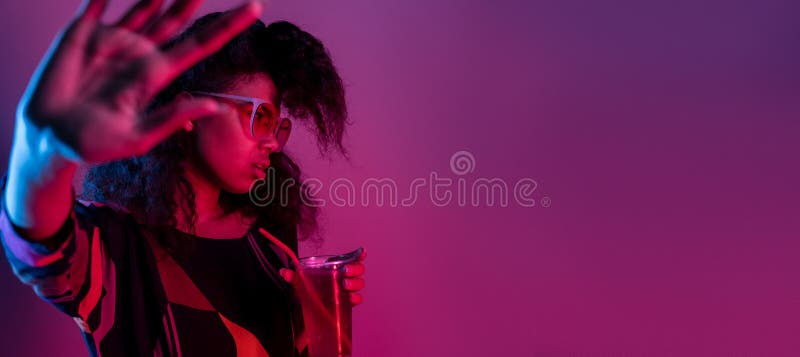 Annoyed fashion young african girl black woman wear stylish pink glasses hold drink say no refuse with stop hand gesture isolated on party purple studio background, banner website design, copy space. Annoyed fashion young african girl black woman wear stylish pink glasses hold drink say no refuse with stop hand gesture isolated on party purple studio background, banner website design, copy space
