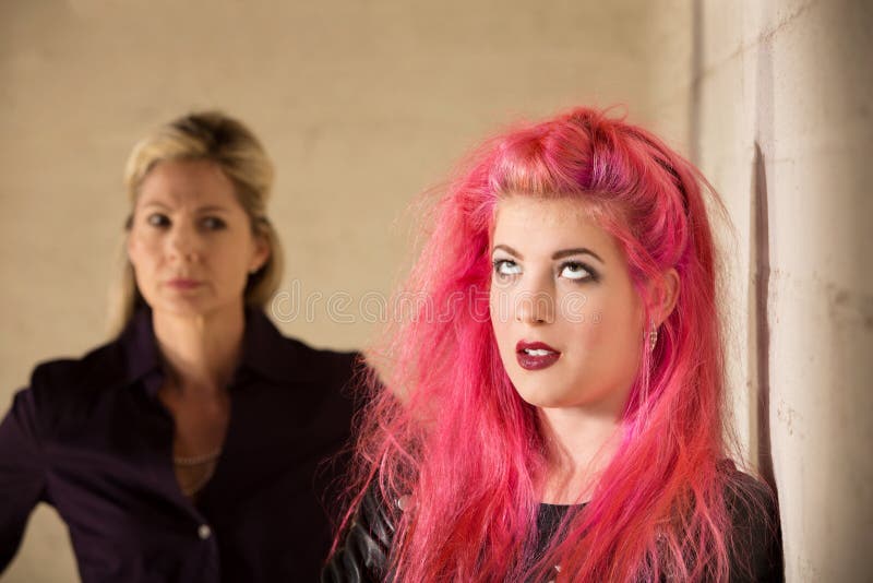 Annoyed girl in pink hair with upset parent. Annoyed girl in pink hair with upset parent