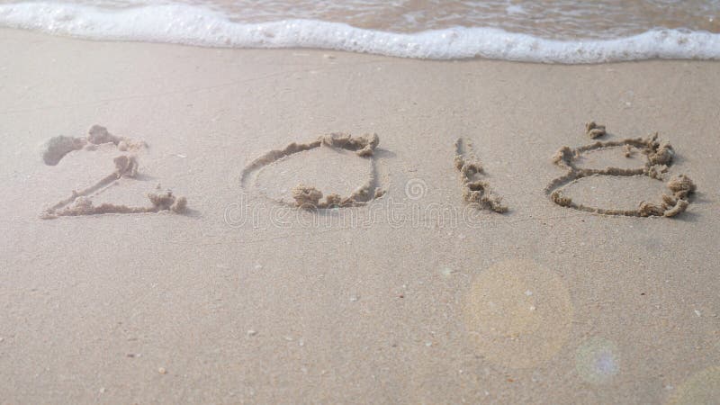 Ano novo feliz 2018 2018 escrevem no Sandy Beach com respingo da onda fotos de stock
