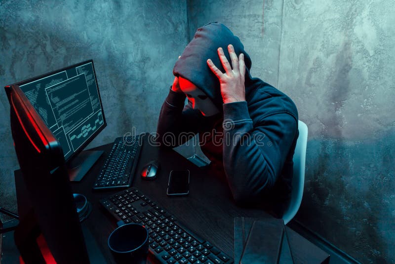 Anonymer Internet-Hacker mit einer am Tisch sitzenden Maske und mit einem Computer stockfoto