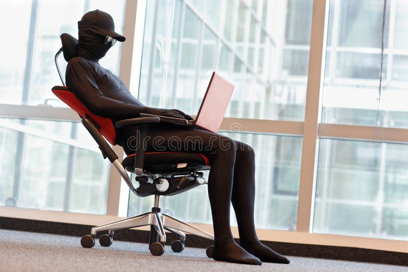 Anonymous hacker working with laptop in office royalty free stock photo