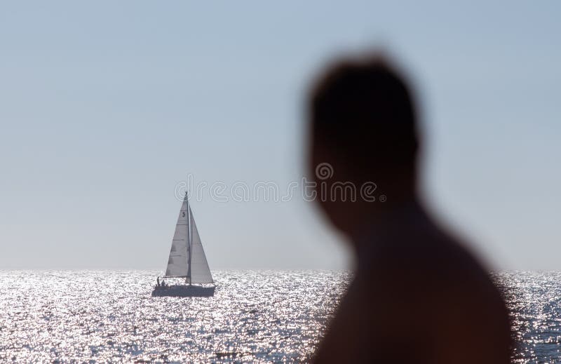Anonymous man watching a sailboat