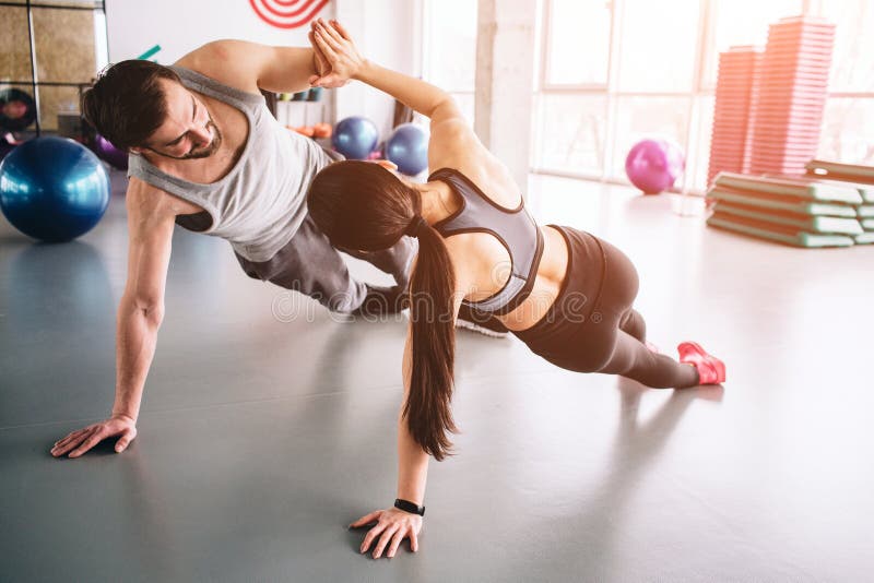 Another picture of two people standing in a side plank position on one hand and holding each other with the other hands royalty free stock photography Another picture of two people standing in a side plank position on one hand and holding each other with the other hands royalty free stock photography