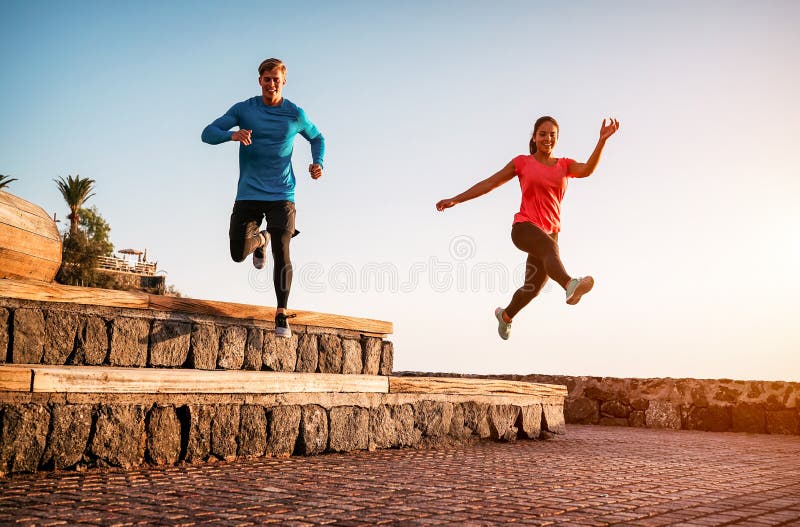 Anpassa paret att köra en arbetsrunda på solnedgången utomhus - sportiga unga människor som joggar bredvid stranden