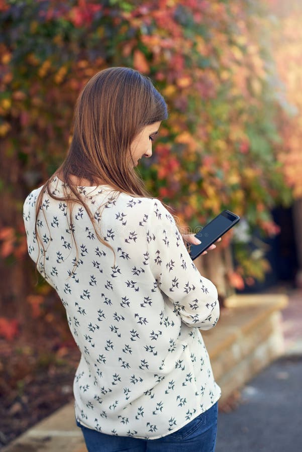 Anseende för ung kvinna i en höstgata som smsar på hennes mobiltelefon arkivbilder Anseende för ung kvinna i en höstgata som smsar på hennes mobiltelefon arkivbilder