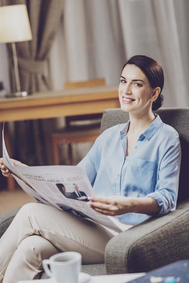 Ansehnlicher Manager, der in einem Stuhl mit Zeitung sitzt stockfoto
