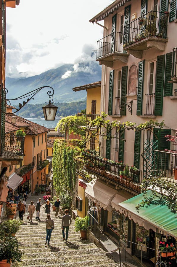 Ansicht der Gasse im Abhang, der Gebäude mit Winde und des Sees Como in Bellagio lizenzfreie stockbilder Ansicht der Gasse im Abhang, der Gebäude mit Winde und des Sees Como in Bellagio lizenzfreie stockbilder