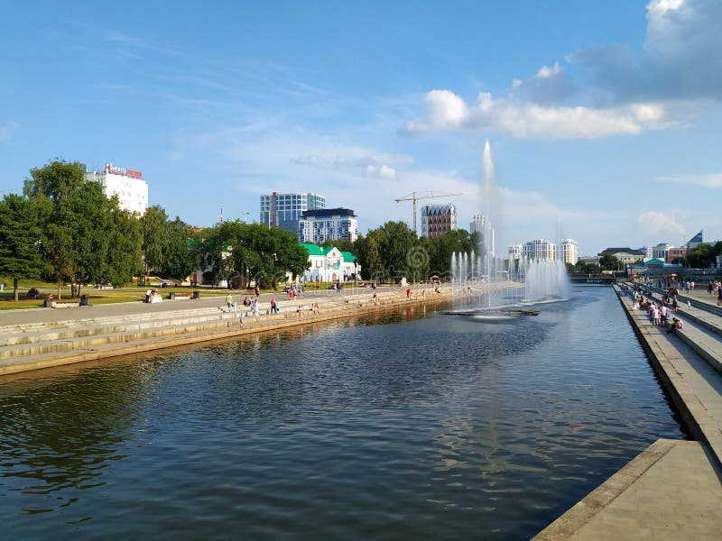 Ansicht der Ufergegend. Fluss mit Brunnen. Am Ufer befinden sich die Stufen der Asphaltstraße. Menschen gehen, es gibt Gebäude u lizenzfreie stockfotos Ansicht der Ufergegend. Fluss mit Brunnen. Am Ufer befinden sich die Stufen der Asphaltstraße. Menschen gehen, es gibt Gebäude u lizenzfreie stockfotos
