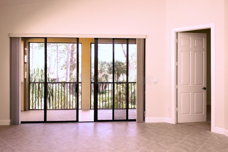 View of balcony from inside house showing sliding glass doors and open door with tiled floor. View of balcony from inside house showing sliding glass doors and open door with tiled floor.