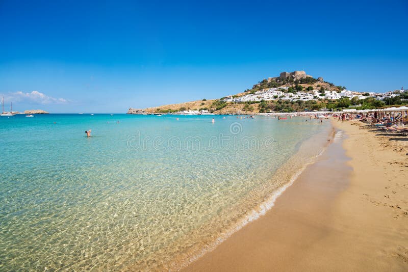 Ansicht des sandigen Strandes in der Bucht von Lindos, Akropolis in Hintergrund R stockfotografie Ansicht des sandigen Strandes in der Bucht von Lindos, Akropolis in Hintergrund R stockfotografie